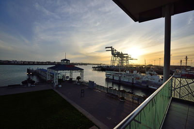 Pier at harbor against sky during sunset