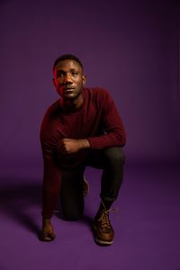 Portrait of young man standing against colored background