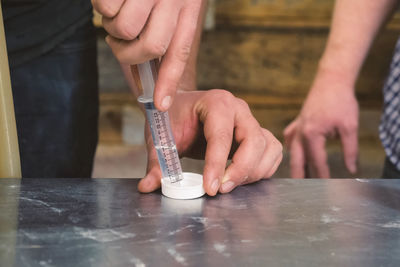 Cropped image of man holding syringe at table