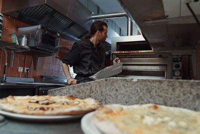 Chef preparing italian pizza in restaurant kitchen 