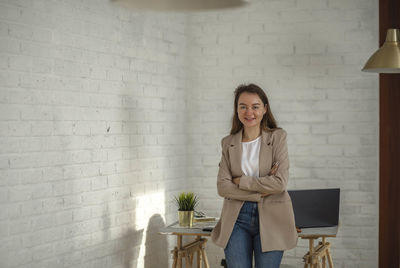 Happy young businesswoman in office. manager smiling leans on table with his arms crossed on chest