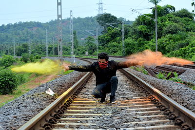 Man throwing powder paint while crouching on railroad track