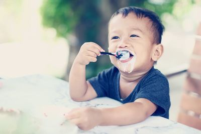 Close-up of smiling boy looking away while having food on table