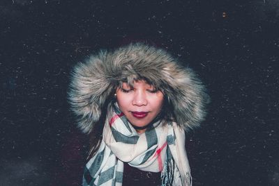 Portrait of young woman against black background