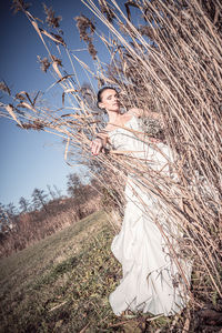 Bride standing by dry plants