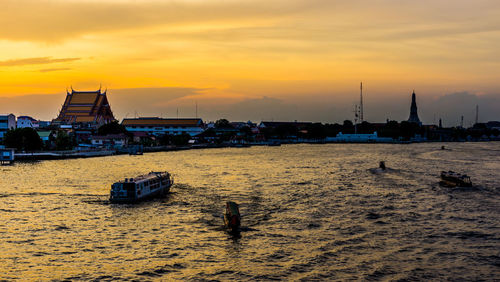 Boats in sea against sky during sunset