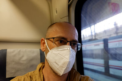 Close-up of man wearing mask sitting in train