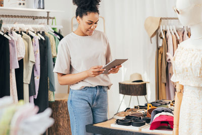 Smiling woman using digital tablet at clothing store