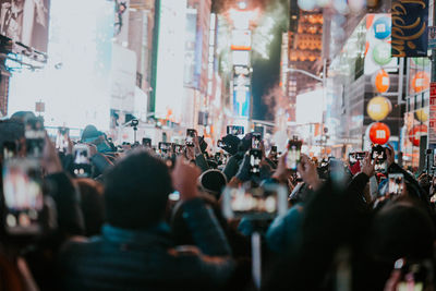 Crowd photographing on illuminated street at night