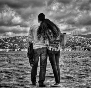 Rear view of woman looking at sea against cloudy sky