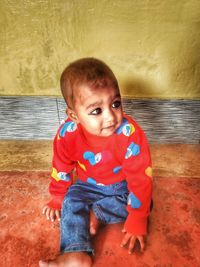 Portrait of cute boy sitting on floor