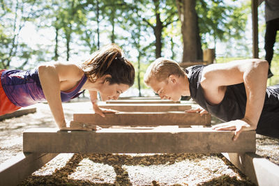 Side view of couple doing push-ups at outdoor gym