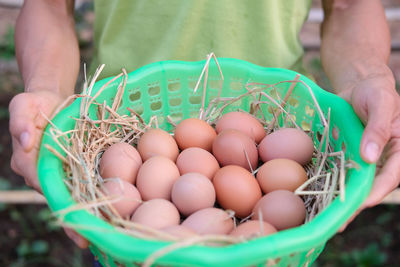 Midsection of person holding vegetables in basket