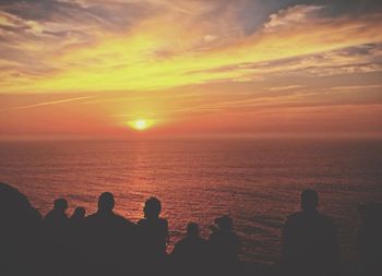 Silhouette people by sea against sky during sunset