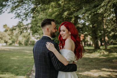 Young couple standing against trees