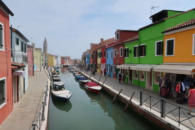 Boats moored in canal amidst buildings against sky