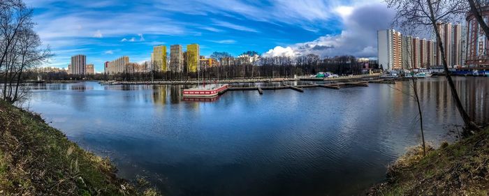 Scenic view of river by buildings against sky