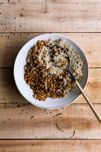 From above white rice mixed with beans in bowl with spoon on wooden rustic table