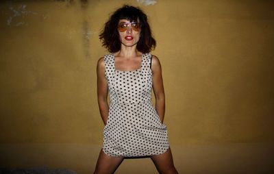 Portrait of a beautiful young woman standing against wall