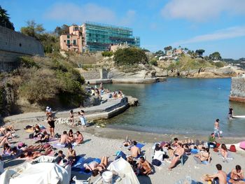 People at beach against sky in city