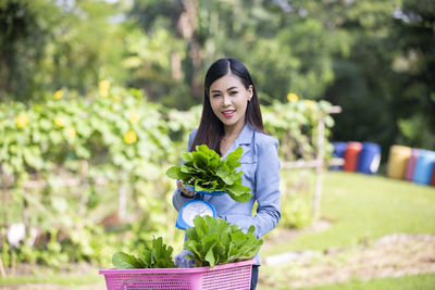 Portrait of beautiful woman holding flower in standing against plants