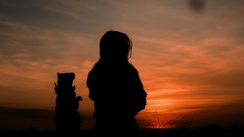 Silhouette woman standing against orange sky