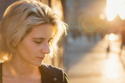 Young blond woman portrait in sunset light outdoor on a city street