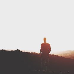 Woman standing on landscape at sunset