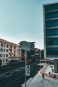 Road by buildings against sky in city