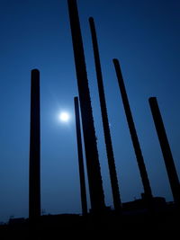 Low angle view of silhouette buildings against clear blue sky