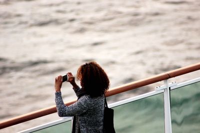 Side view of woman photographing sea