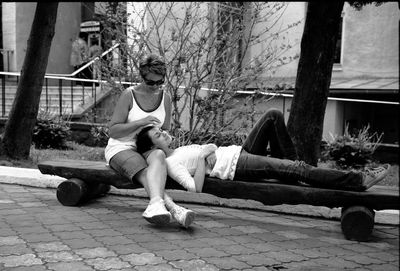 Young daughter sleeping on mothers lap outdoors