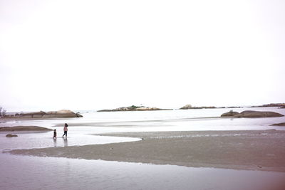 Man walking on beach against clear sky