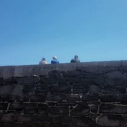 Low angle view of people on steps against clear sky