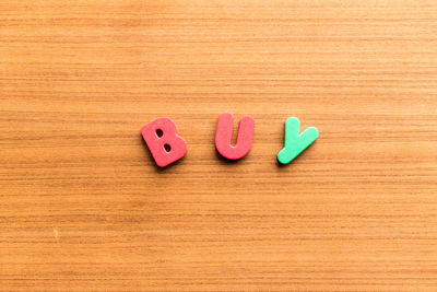 High angle view of colorful buy text on wooden table