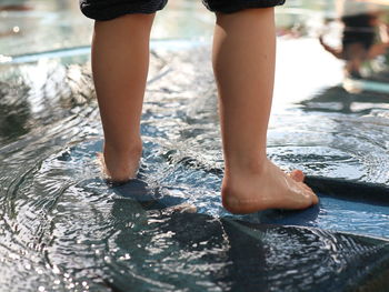 Low section of man standing in swimming pool