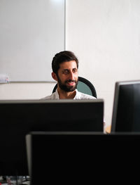 Young man using smart phone while sitting in office