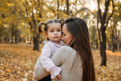 Ways to carry a toddler. close up outdoors portrait of happy family mom and toddler baby girl in