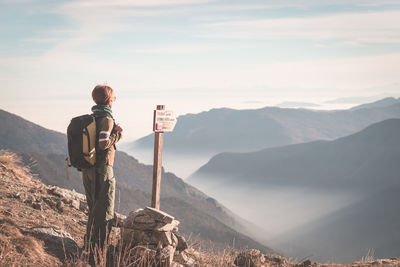 Rear view of woman standing on mountain during foggy weather