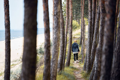 Woman hiking in forest along seashore. person actively spending vacations. summer trip