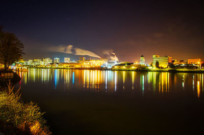 Illuminated harbor by sea against sky at night