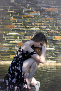 Side view of young woman sitting outdoors