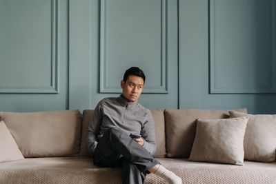 Young woman using laptop while sitting on sofa at home