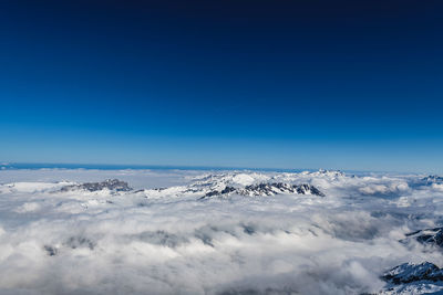 Scenic view of snowcapped mountains against blue sky