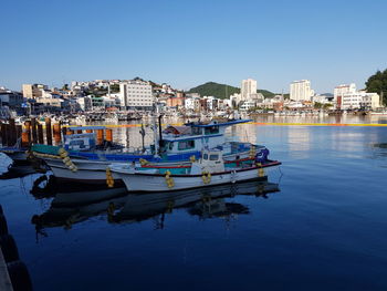 Boats moored in canal by buildings against blue sky