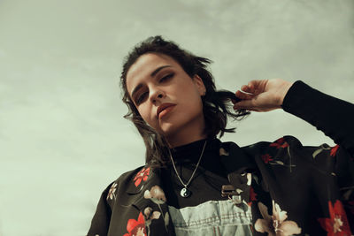 Portrait of young woman standing against sky