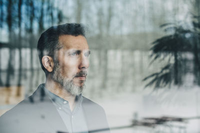 Close-up of thoughtful businessman seen through glass window at office