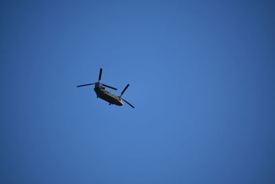 Low angle view of airplane flying against clear blue sky