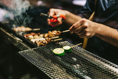 Midsection of person preparing food on barbecue grill