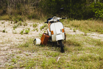 Abandoned motorcycle by luggage over grassy land